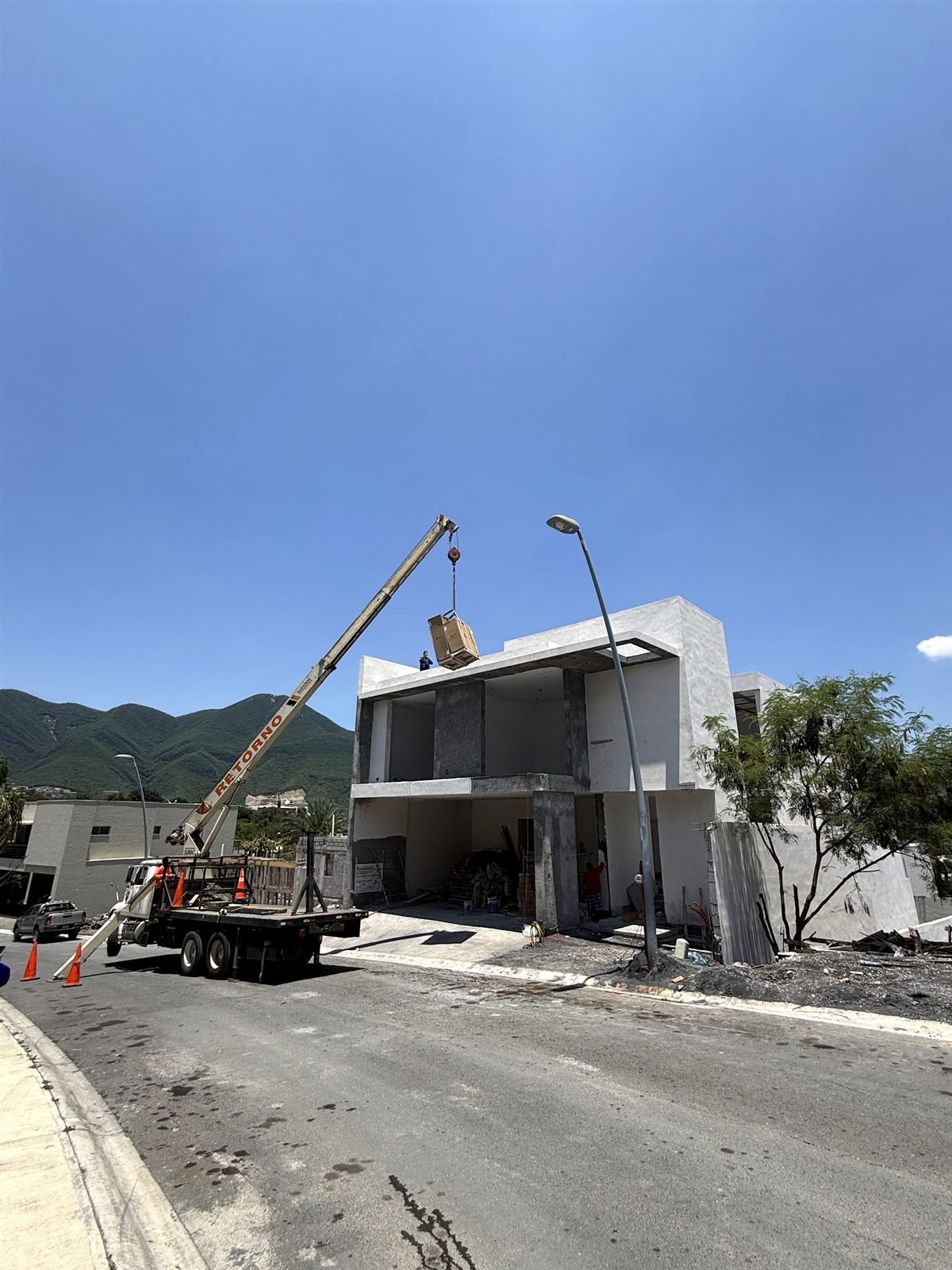 Grúa subiendo un equipo a la azotea de una residencia en construcción